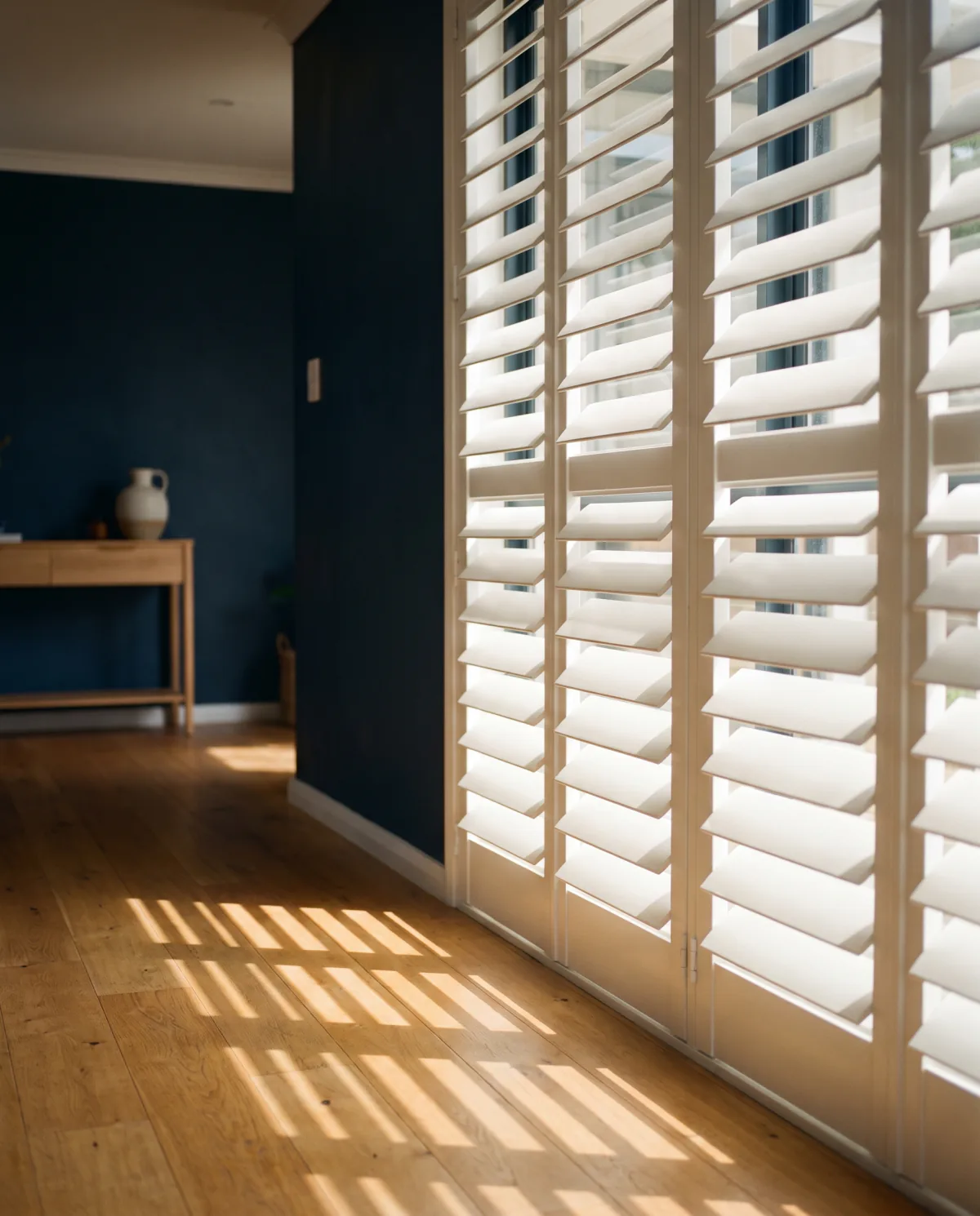Plantation shutters with their louvres tilted part open in a warm room